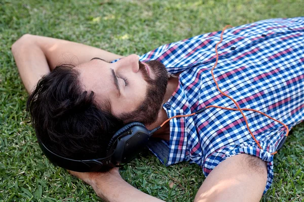Hombre escuchando música en la hierba — Foto de Stock
