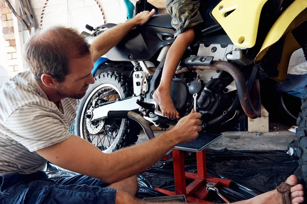 Ragazzo aiutare papà con fissaggio moto — Foto Stock