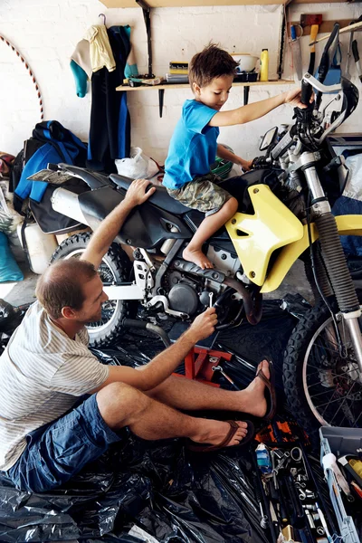 Хлопчик допомагає тату з фіксуючим мотоциклом — стокове фото
