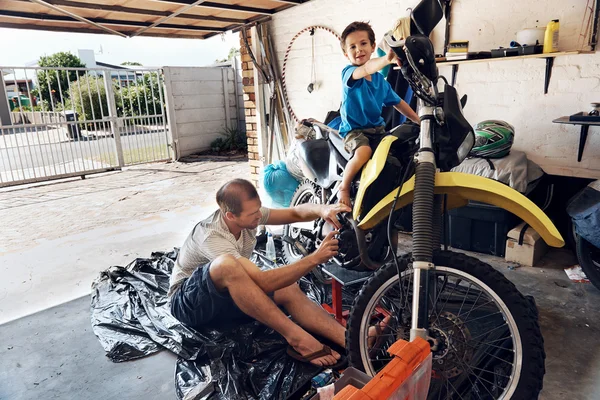 Junge hilft Papa beim Reparieren von Motorrad — Stockfoto