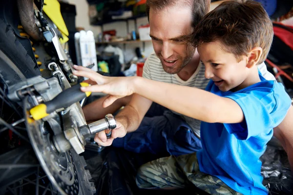 Jongen helpen vader met vaststelling motorfiets — Stockfoto