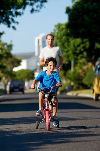 Father teaching son learning to ride bicycle — Stock Photo, Image