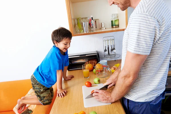 Ragazzo guardando padre tagliato frutta e verdura — Foto Stock