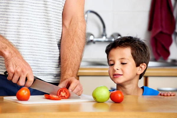 Jongen horloges vader snijden tomaat — Stockfoto