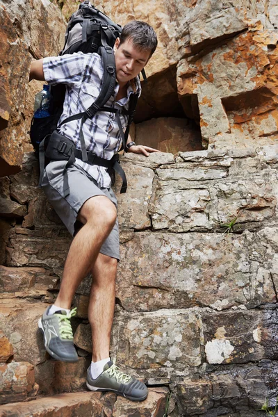 Man climbing down steep mountain — Stock Photo, Image