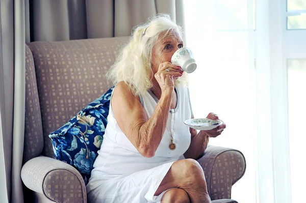 Ältere Dame sitzt auf Sofa — Stockfoto