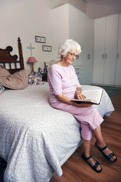 Frau auf dem Bett liest Bibel — Stockfoto