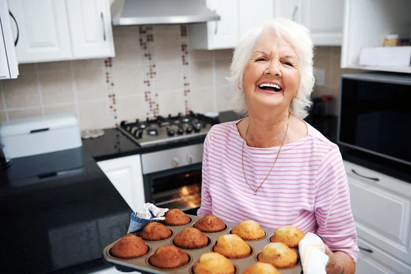 Smějící se důchodce drží podnos muffiny — Stock fotografie