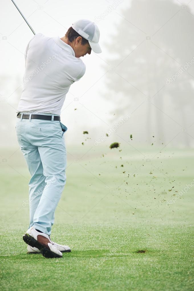 Golfer hitting golf shot with club