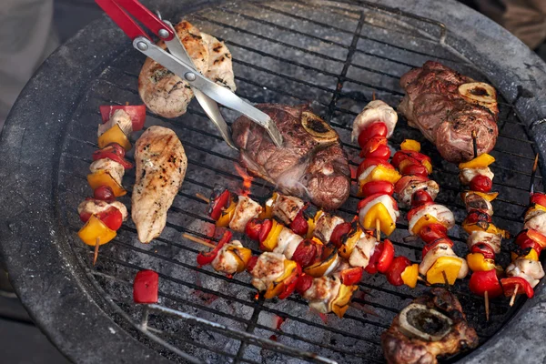 Viande savoureuse et brochettes sur barbecue — Photo