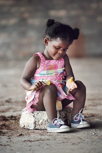Африканский ребенок сидит на скале — стоковое фото