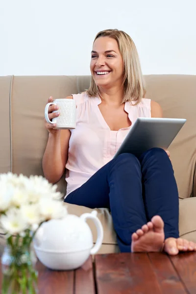 Kvinna på soffa läser e-post på Tablet PC — Stockfoto