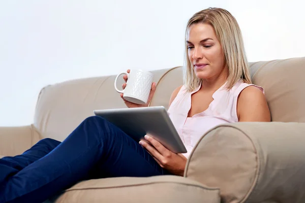 Frau auf Sofa liest E-Mail auf Tablet — Stockfoto