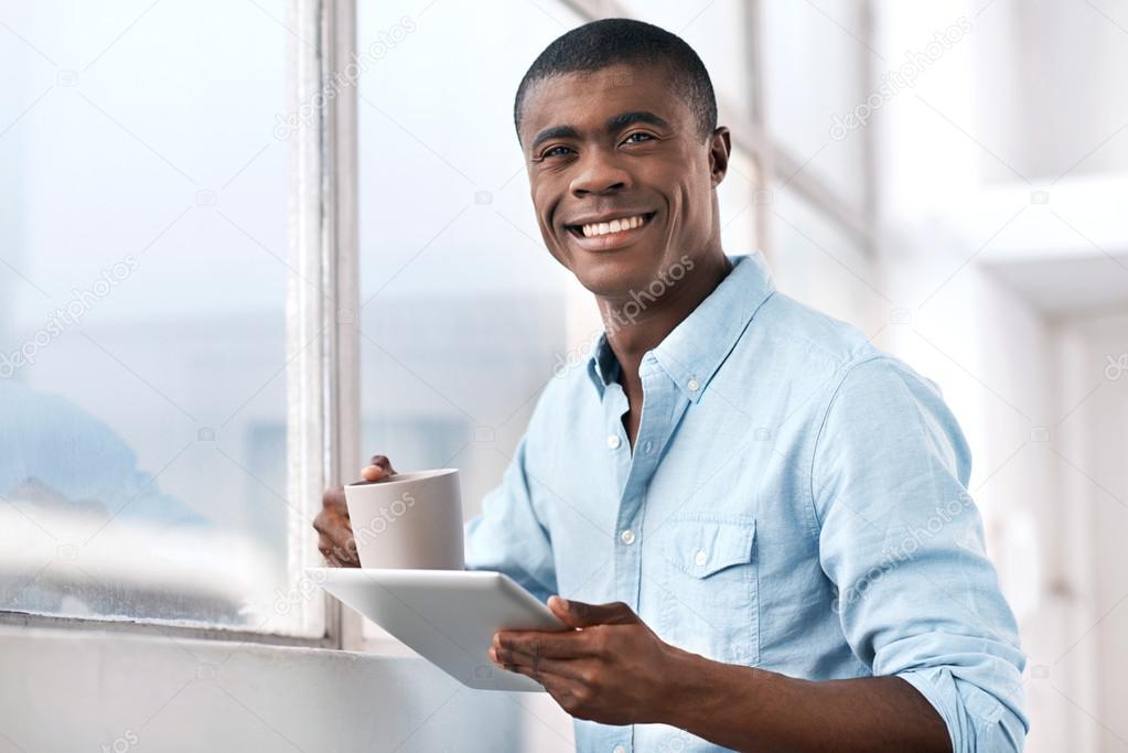 african man with coffee and tablet