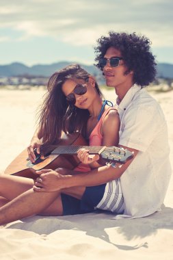 hispanic couple playing guitar on beach clipart