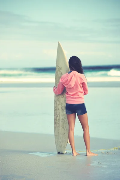 Donna in piedi con tavola da surf in spiaggia — Foto Stock