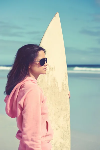 Mujer de pie con tabla de surf en la playa — Foto de Stock