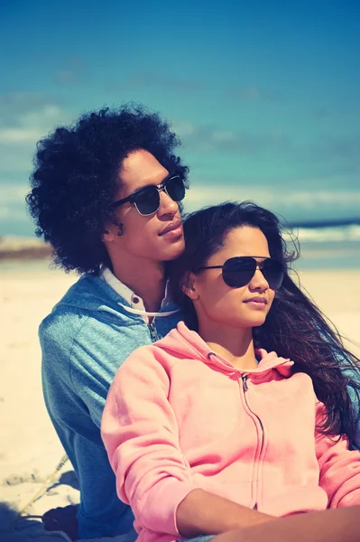 Latino par sitter på stranden — Stockfoto