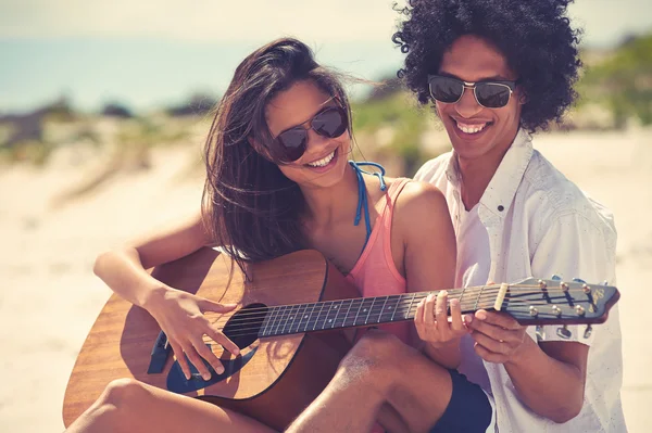 Spansktalande par spelar gitarr på stranden — Stockfoto