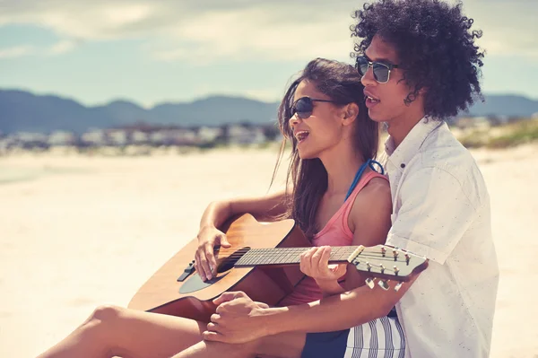 Spansktalande par spelar gitarr på stranden — Stockfoto