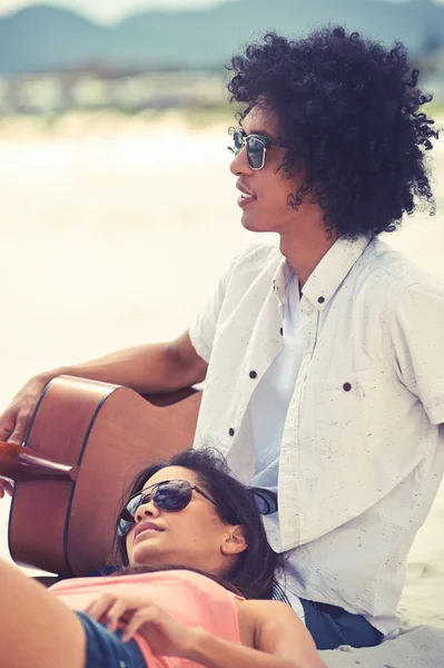 Hispanic couple playing guitar on beach — Stock Photo, Image