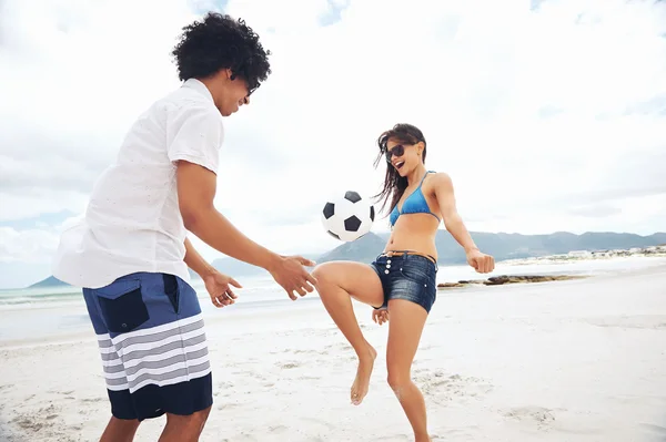 Latino couple playing soccer on beach — Stock Photo, Image