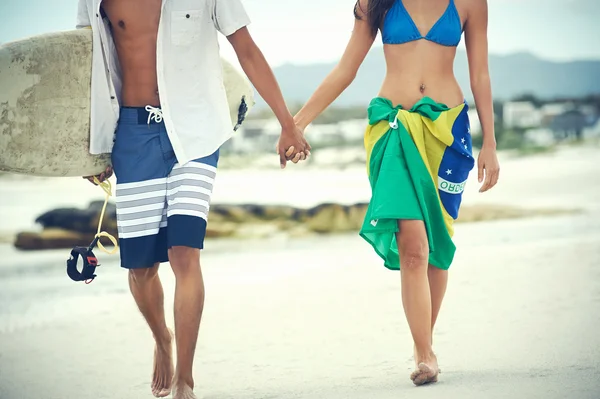 Couple marchant avec planche de surf et drapeau comme sarong — Photo