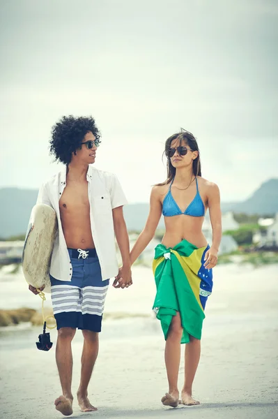Couple walking with surfboard and flag as sarong — Stock Photo, Image