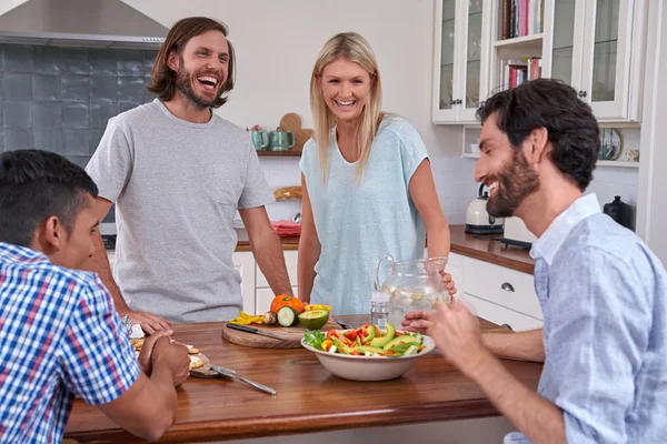 Amis riant avec salade dans la cuisine — Photo