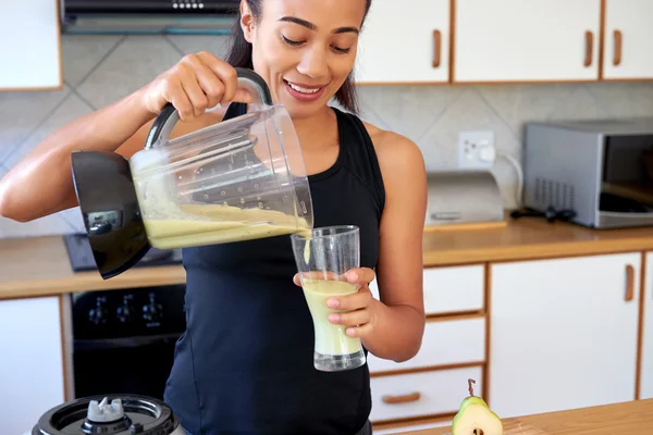 Woman pouring green smoothie into glass — Stock Photo, Image