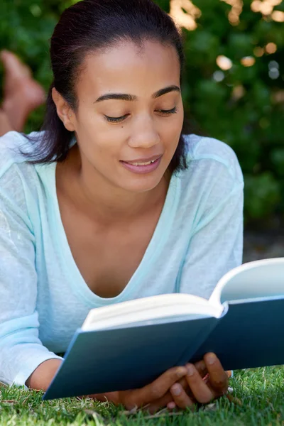 Schöne Frau liest ein Buch im Garten — Stockfoto