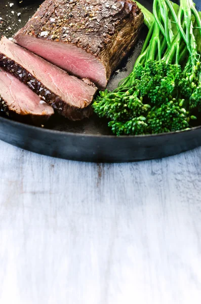 Saftiges Steak auf schwarzer Pfanne mit frischem grünen Gemüse — Stockfoto