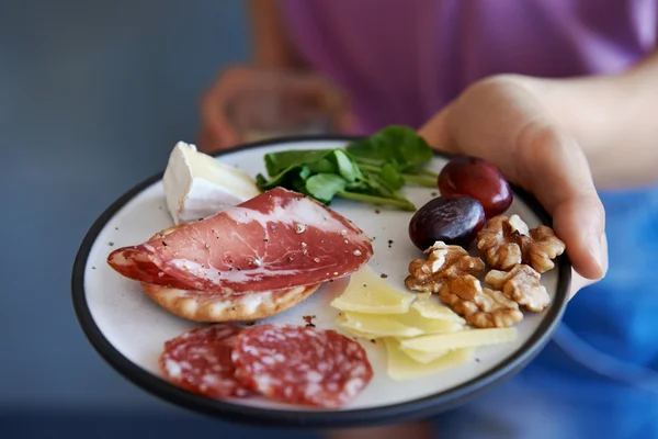 Hands holding plate of snacks