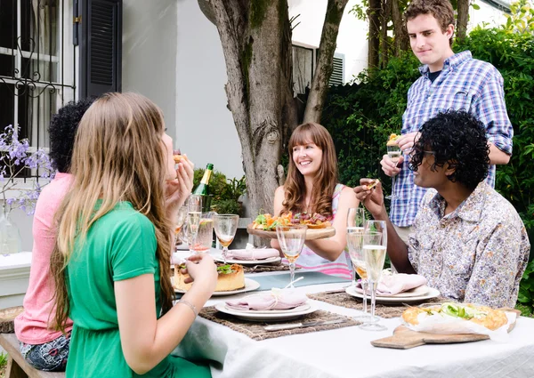 Amigos disfrutando de comida y bebidas en una reunión —  Fotos de Stock