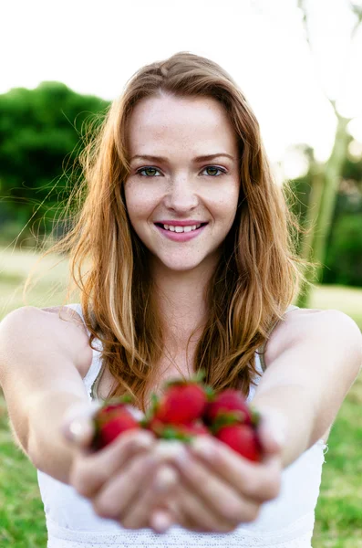 Beautiful smiling woman in garden with strawberries — ストック写真