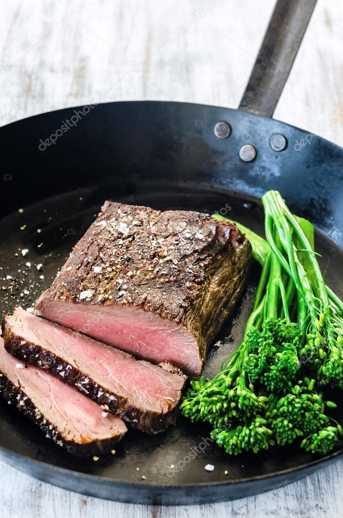 Close up of gourmet steak with seasoning and greens