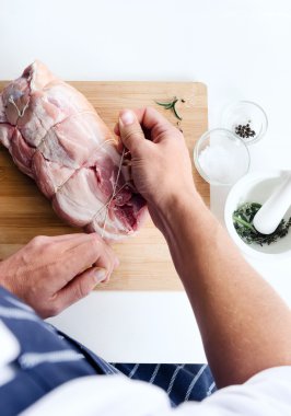 Chef hands tying rolled raw pork clipart