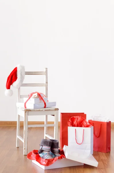 Christmas shopping bags in empty room with chair — Stock Photo, Image