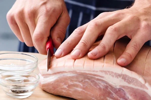 Les mains de boucher coupant la viande — Photo