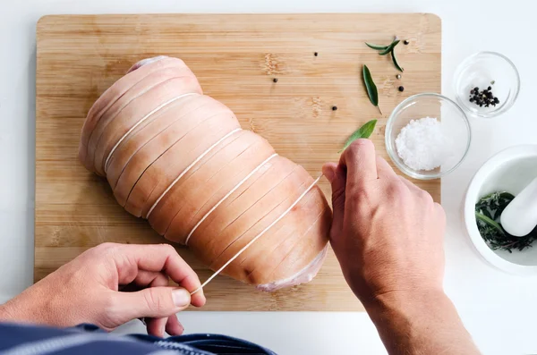Руки шеф-повара вяжут сырую свинину — стоковое фото