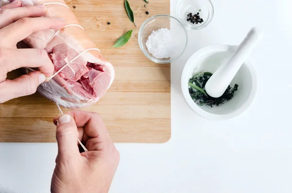 Juru masak mengikat daging babi mentah yang digulung — Stok Foto