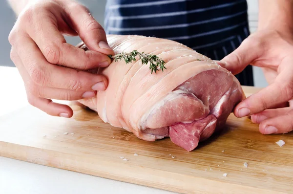 Chef mãos colocando tomilho fresco no ombro de porco cru — Fotografia de Stock