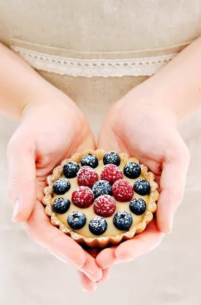 Женщина в фартуке держит фруктовый десерт — стоковое фото
