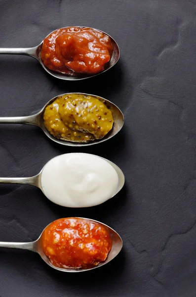 Different types of condiments on spoons — Stock Photo, Image