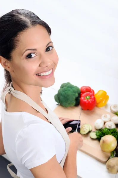 笑顔の女性が台所で野菜をスライス — ストック写真