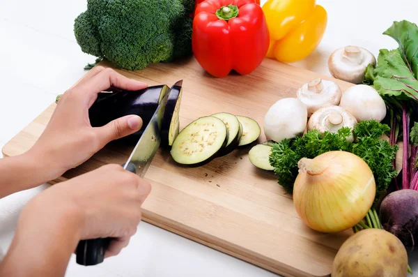 Manos sosteniendo cuchillo cortando verduras — Foto de Stock