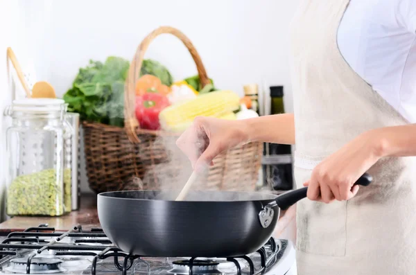 Vrouw permanent door kachel koken en de voorbereiding van de maaltijd — Stockfoto