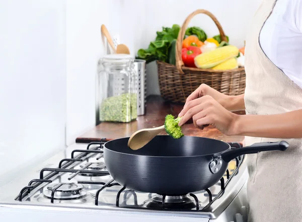 Wanita berdiri dengan kompor memasak dan menyiapkan makanan — Stok Foto