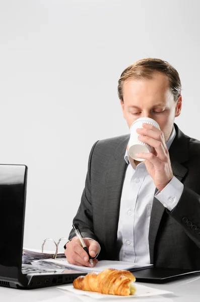 Businessman drinks coffee while working — Zdjęcie stockowe