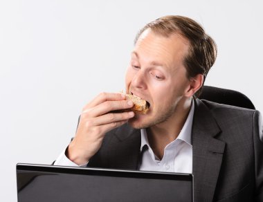 Multi tasking businessman eats and works clipart